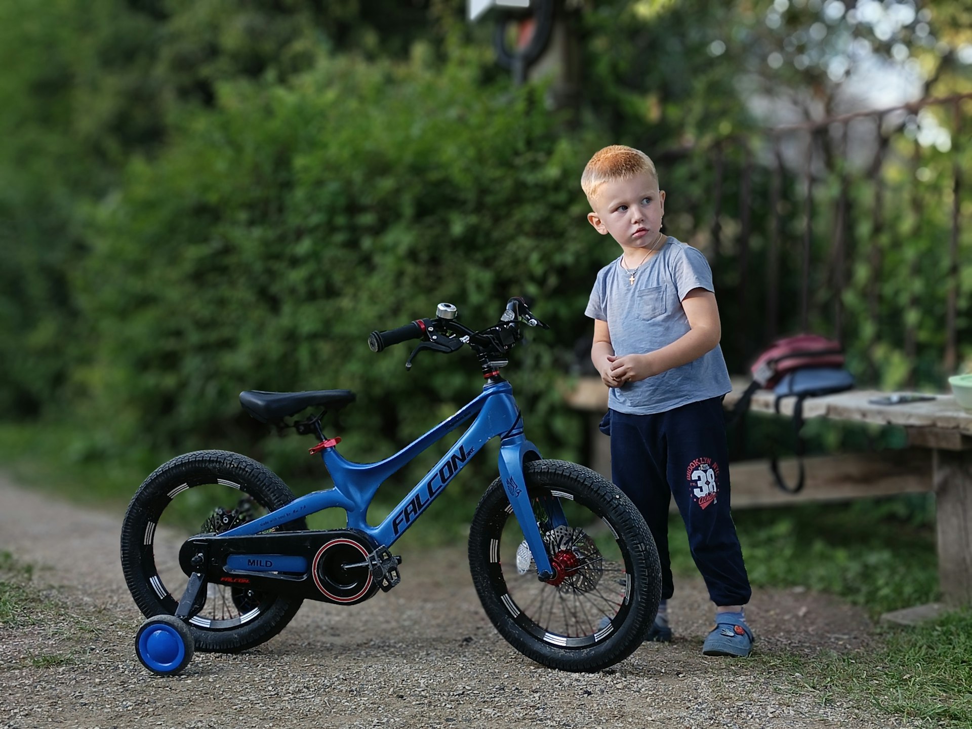 A young boy standing next to a blue bike
